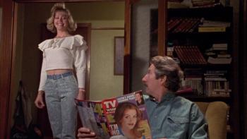 The Castle: A middle-aged White man sat down holding a magazine, while a younger White woman stands next to him looking proud