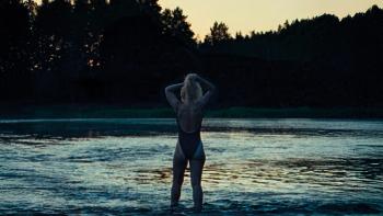The Chronology of Water movie: Imogen Poots stands at the water's edge at dusk