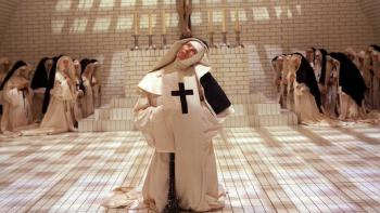 The Devils: Nuns in habits stand in a tiled room, one in front with a large black cross