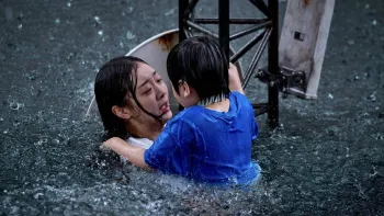 The Great Flood movie: Kim Da-mi holds little boy in blue shirt clinging to metal buoy center as both are neck-deep in water