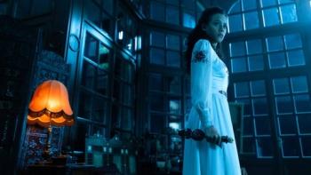 The Invitation Movie: A woman in a white dress holds an ornate candlestick