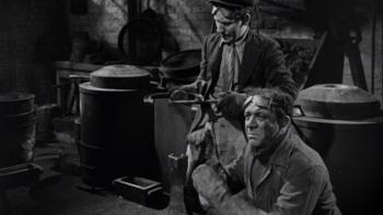 The Lavender Hill Mob: Two White men are shown working in a metal factory wearing gloves and goggles