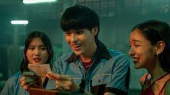 The Lost Lotteries movie: sitting Thai man center looks at lottery ticket as Thai woman on left and Thai woman on right look on