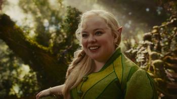 The Magic Faraway Tree film still: Nicola Coughlan as an elf in a green outfit smiles in a sunlit forest.