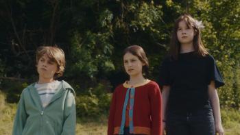 The Magic Faraway Tree film still: Three children standing in a grassy area, looking ahead.