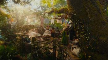 The Magic Faraway Tree film still: Sunlit garden with people, colorful clothes hanging, and large tree trunk in foreground.