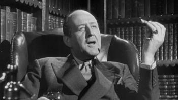 The Man in the White Suit: Cecil Parker sits at a desk smoking a cigar