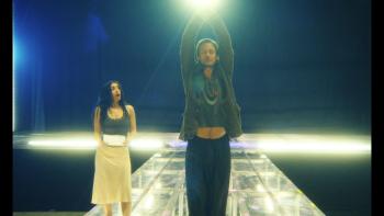 The Moment movie: Charli XCX stands on stage, her mouth agape, looking at Alexander Skarsgard, whose hands are in the air like a dancer