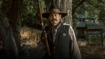 The Night They Came Home movie: A white man sheriff with rifle center stands in front of a tree and a shack