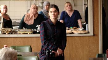 The Old Oak: Ebla Mari holds a camera as she stands in front of other women working in a community kitchen