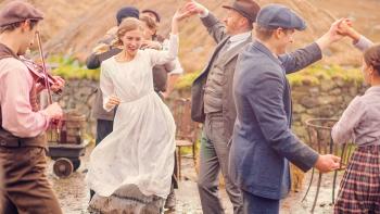 The Road Dance: A young woman dances in a white dress, surrounded by other villagers dancing in the open air