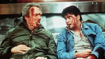 The Rookie (1990) movie: Charlie Sheen right, Clint Eastwood left, each bloodied with cigars in mouths, slumped against an airport baggage carousel