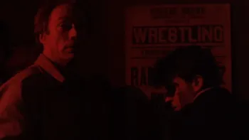 The Rookie (1990) movie: Charlie Sheen right, Clint Eastwood left, in front of boxing poster, look around in dark red light