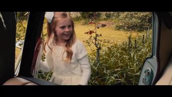 A little girl smiles as she peers inside a car window