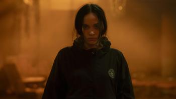 The Shadow Strays movie: Indonesian woman with black hair in black hoodie center walks forward in front of hazy orange background