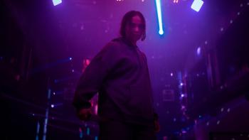 The Shadow Strays movie: Indonesian woman in dark hoodie center holds knife in right hand while standing alone in purple hued nightclub