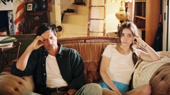 The Sweet East Movie: A man sits on a couch with a look of concern while a young woman looks straight at the camera