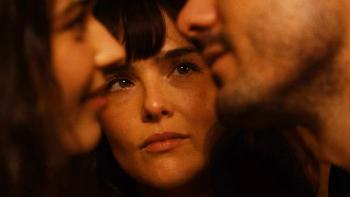 The Threesome movie: Extreme closeup of the faces of Ruby Cruz and Josh Hauer-King beaming at each other, Zoey Deutch between them