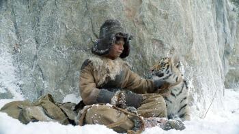 The Tiger's Nest: A young Indian boy leans against a rock, a baby tiger beside him, with snow on his clothes and face.