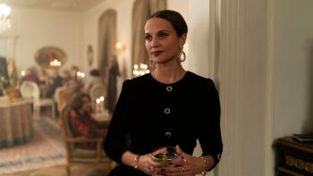 The Wizard of the Kremlin: Elegant woman in black dress holding a glass at a formal gathering indoors