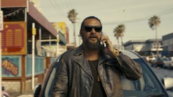 The Wrecking Crew: Jason Momoa on a city street on the phone.