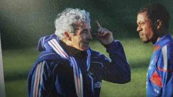 The Bus: A French Football Mutiny Movie: Two men, one Black and one White, in sportswear talking outdoors, with greenery in the background.