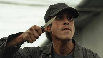 The Debt Collector Movie: Man in a cap holding a knife near his face, intense expression.