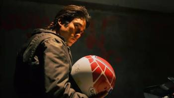 The Debt Collector Movie: Man in a dimly lit room holding a colorful helmet.