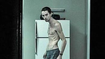 The Machinist Movie: A thin man stands shirtless in front of a refrigerator.