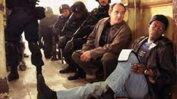 The Negotiator: Two men and soldiers sit on the floor