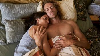 The Secret Woman:  Couple lying in bed, woman resting her head on man's chest, both appear relaxed.