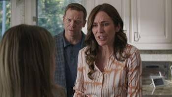 The Seemingly Perfect Family: Woman and man in a kitchen, looking concerned at another person.