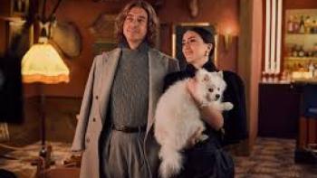 The Storm movie: White man and woman smiling indoors, holding a fluffy white dog.