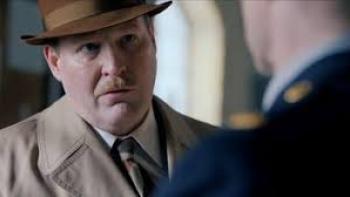 The Swedish Connection Movie: Henrik Dorsin in tan trench coat and hat