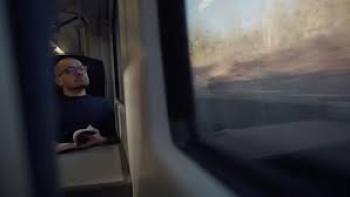 The Thinking Game Movie:  Man reading a book on a train, gazing out the window.