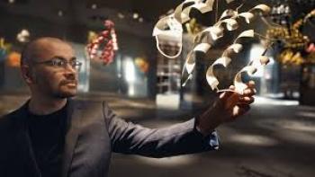 The Thinking Game Movie:  Man in a suit interacting with digital graphics in a dimly lit room.