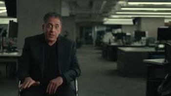 The Widower: Man in a dark suit sitting in a dimly lit office setting.