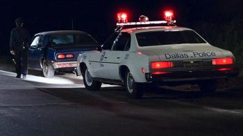 The Thin Blue Line: A police car is shown pulled over behind a blue car on the side of the road with a police officer walking toward the front car