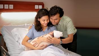 Today We'll Talk About That Day movie: Indonesian woman in hospital bed center holds newborn baby while Indonesian man sits next to her on right also looking at the baby