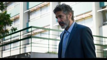A world-weary man in front of a tall building.