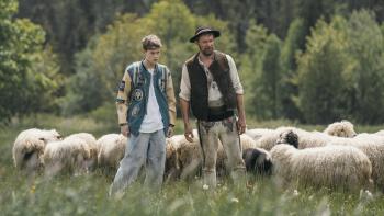 Too Old for Fairy Tales 2: A teen boy and a man stand with a flock of sheep