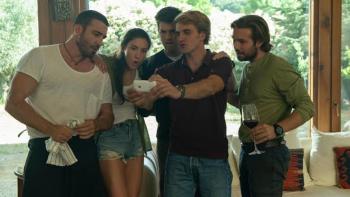 To the Max Movie: Five people gathered, surprised, looking at a smartphone indoors.