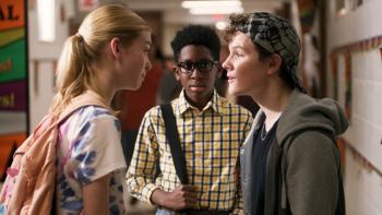 Treasure Trackers movie: Three kids stand together in a school hallway, two - a boy and a girl look at each other with negative intensity