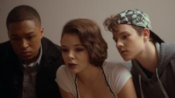 Treasure Trackers movie: Three young teens stand together hovering over something they appear to be looking at.