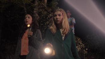 Treasure Trackers movie: Three kids walk in the dark while holding a flashlight