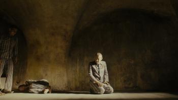 Triumph of the Heart movie: Marcin Kwaśny kneels inside Auschwitz