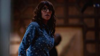 Trust movie: Katey Sagal, wearing glasses and a denim shirt with a flower print, looks at something apprehensively