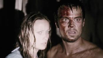 Melissa George and Josh Duhamel have a bright light shining on them. Josh has blood on his face and is shirtless.