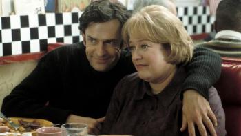 Rupert Everett puts his arm around Kathy Bates in a diner