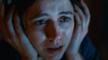 Undertone Movie: Her face lit by a computer screen, Evy looks on the verge of tears and utterly terrified